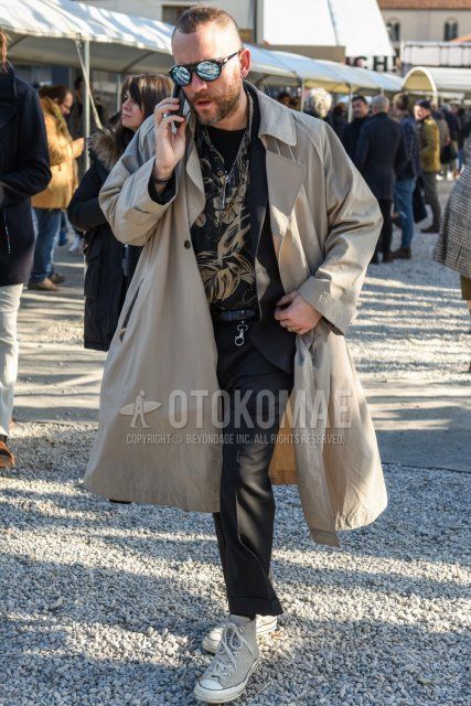Men's fall/winter outfit with plain black sunglasses, plain beige trench coat, black top/inner shirt, plain black t-shirt, plain black leather belt, dark gray plain slacks, dark gray plain cropped pants, and gray high-cut sneakers.