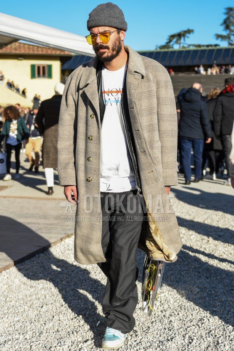 Men's fall/winter coordinate and outfit with plain gray knit cap, plain beige sunglasses, gray checked stainless steel coat, plain black rider's jacket, white graphic t-shirt, plain gray slacks, and white/light blue low-cut sneakers.