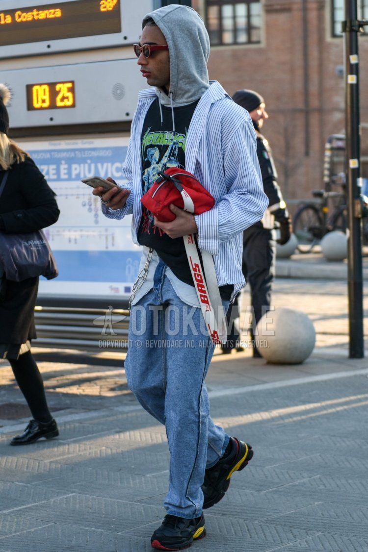 Red solid sunglasses, light blue striped shirt, black graphic sweatshirt, grey solid hoodie, light blue solid denim/jeans, light blue solid sideline pants, Raf Simons Adidas Oswego black low-cut sneakers, red solid shoulder bag Fall/Winter Men's Codes and Outfits.