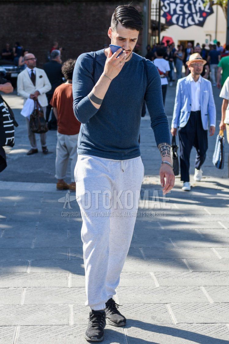 Men's spring/fall/summer coordination and outfit with plain blue long T, plain white/gray sweatpants, and black low-cut sneakers.