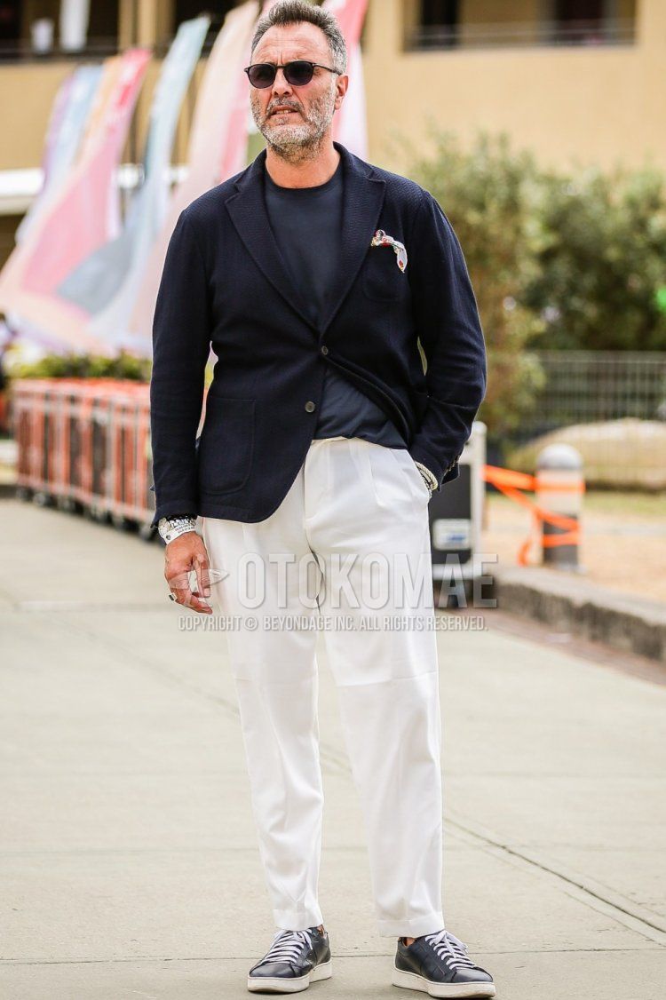 Men's spring and summer coordinate and outfit with plain black sunglasses, plain navy tailored jacket, plain navy t-shirt, plain white cropped pants, plain white slacks, and navy sneakers.