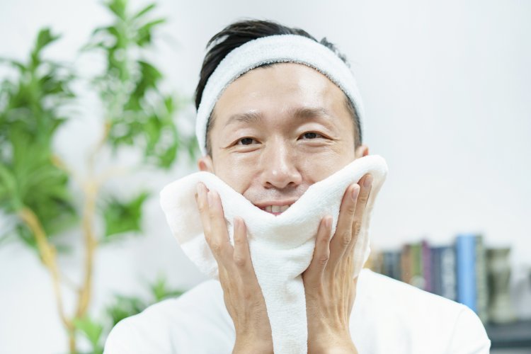 A man wiping his face with a towel