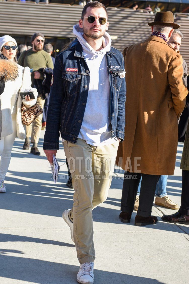 Men's fall/winter coordinate and outfit with plain blue denim jacket, plain white hoodie, plain beige chinos, and white low-cut sneakers.
