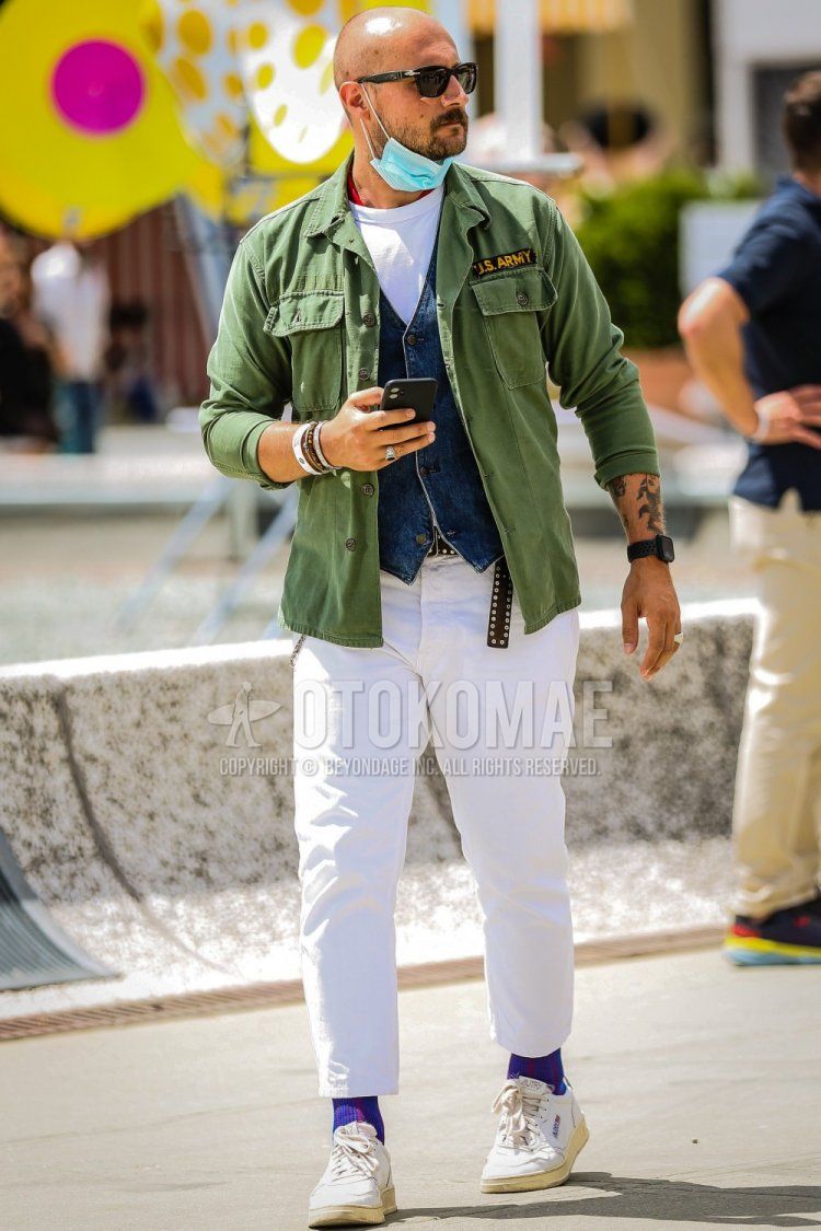 Summer/spring men's coordinate and outfit with Persol plain black sunglasses, plain olive green M-65, plain blue casual vest, plain white t-shirt, plain black leather belt, plain white ankle pants, purple/navy striped socks, white sneakers.