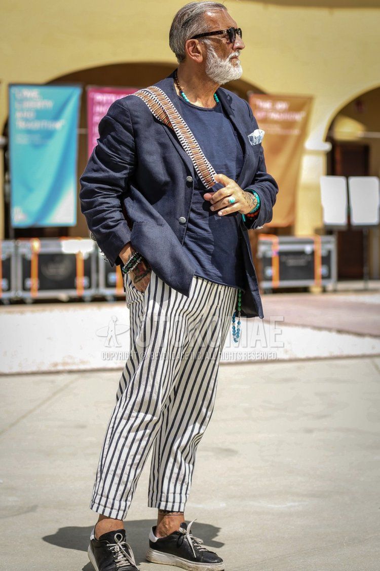 Men's spring/summer coordinate and outfit with plain black sunglasses, plain navy tailored jacket, plain blue/navy t-shirt, white/navy striped ankle pants, black sneakers, and brown bag shoulder bag.