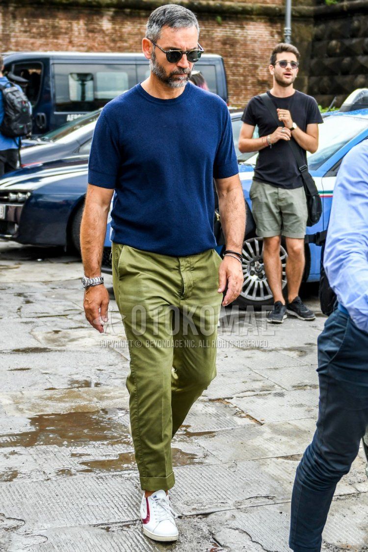 Summer men's coordinate and outfit with plain black sunglasses, knit plain navy t-shirt, olive green plain chinos and white low-cut sneakers.