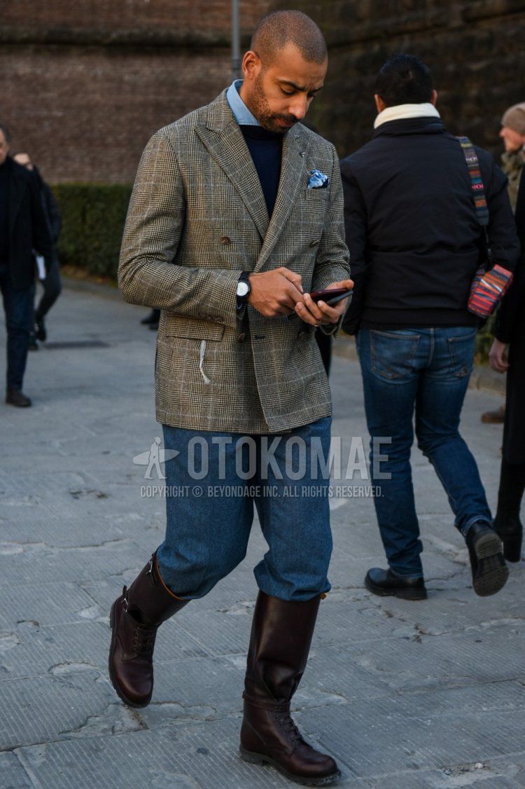Men's spring/autumn coordinate and outfit with gray checked tailored jacket, solid navy sweater, solid light blue denim/chambray shirt, solid gray slacks, and brown boots.
