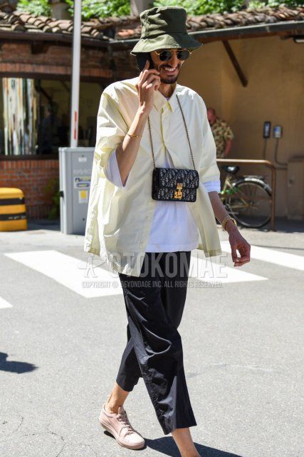 Olive green solid hat, black and gold solid sunglasses, yellow solid shirt, white solid t-shirt, dark gray solid cotton pants, solid cropped pants, pink low cut sneakers, Dior black and gray bag shoulder bag for spring and fall. Men's Codes and Outfits.