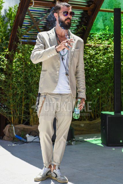 Men's spring/summer coordinate and outfit with teardrop brown/silver solid sunglasses, solid white t-shirt, white low-cut sneakers, and solid beige suit.