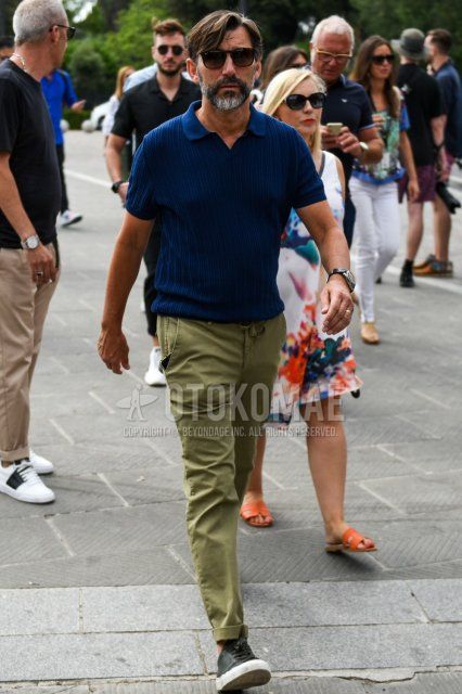 Men's summer coordinate and outfit with plain black Ray-Ban sunglasses, plain navy polo shirt, plain olive green chinos, and black low-cut sneakers.