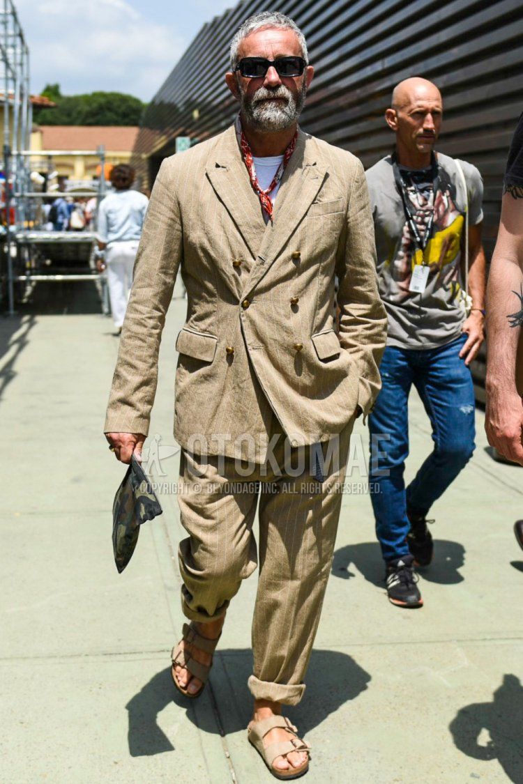 Men's spring/summer coordinate and outfit with plain black sunglasses, red stole bandana/neckerchief, plain white t-shirt, beige leather sandals, olive green camouflage clutch/second bag/drawstring, and beige striped suit.