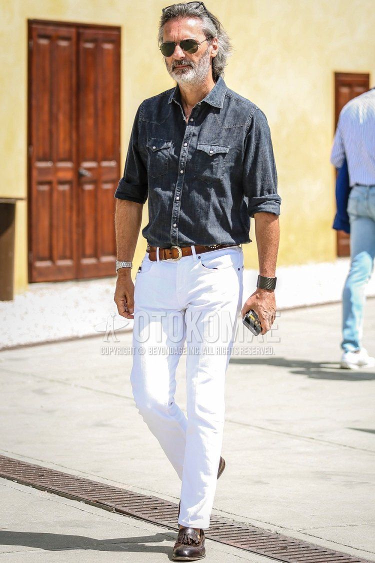 Men's spring/summer coordinate and outfit with plain black sunglasses, plain dark gray/blue shirt, plain brown leather belt, plain white denim/jeans, and brown tassel loafer leather shoes.