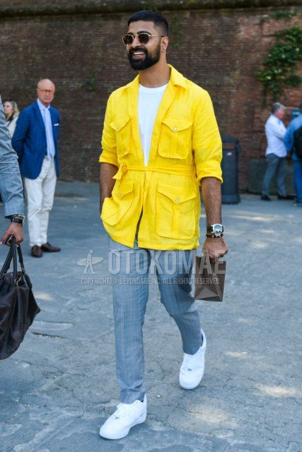 Round Ray-Ban plain black sunglasses, plain yellow safari jacket, plain white t-shirt, gray checked slacks, and Nike Air Force 1 white low-cut sneakers for men in spring, summer and fall.