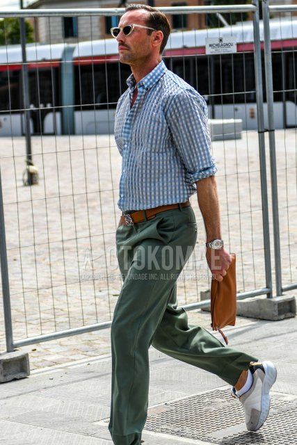 Men's summer coordinate and outfit with solid color sunglasses, light blue checked shirt, solid color brown leather belt, solid color green wide pants, solid color white socks, white low cut sneakers, solid color brown clutch bag/second bag/drawstring.