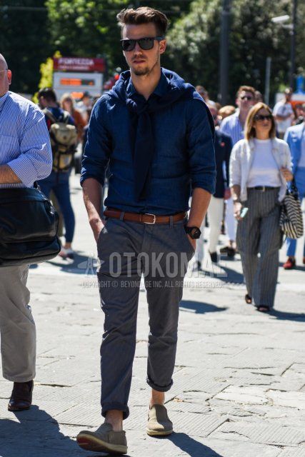 Men's spring/summer coordinate and outfit with plain navy sunglasses, plain navy shirt, plain brown leather belt, plain gray slacks, and gray slip-on sneakers.