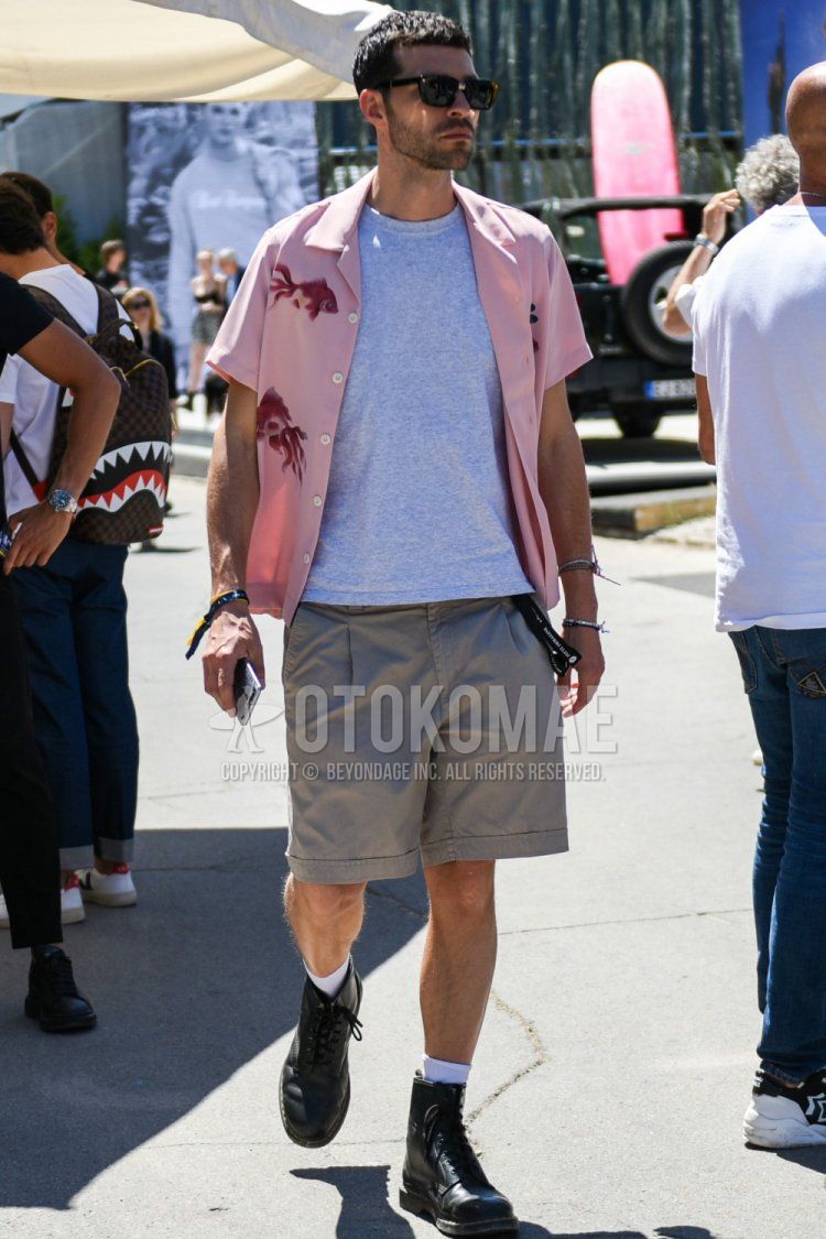 A summer men's coordinate and outfit with plain black sunglasses, short-sleeved pink graphic shirt, short-sleeved plain gray T-shirt, plain beige shorts, plain chinos, plain white socks, and black boots.