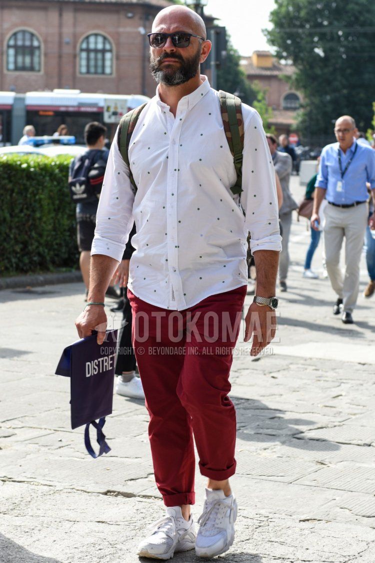 Men's spring, summer, and fall coordinate and outfit with plain black sunglasses, white dotted shirt, red plain cotton pants, and white low-cut sneakers.