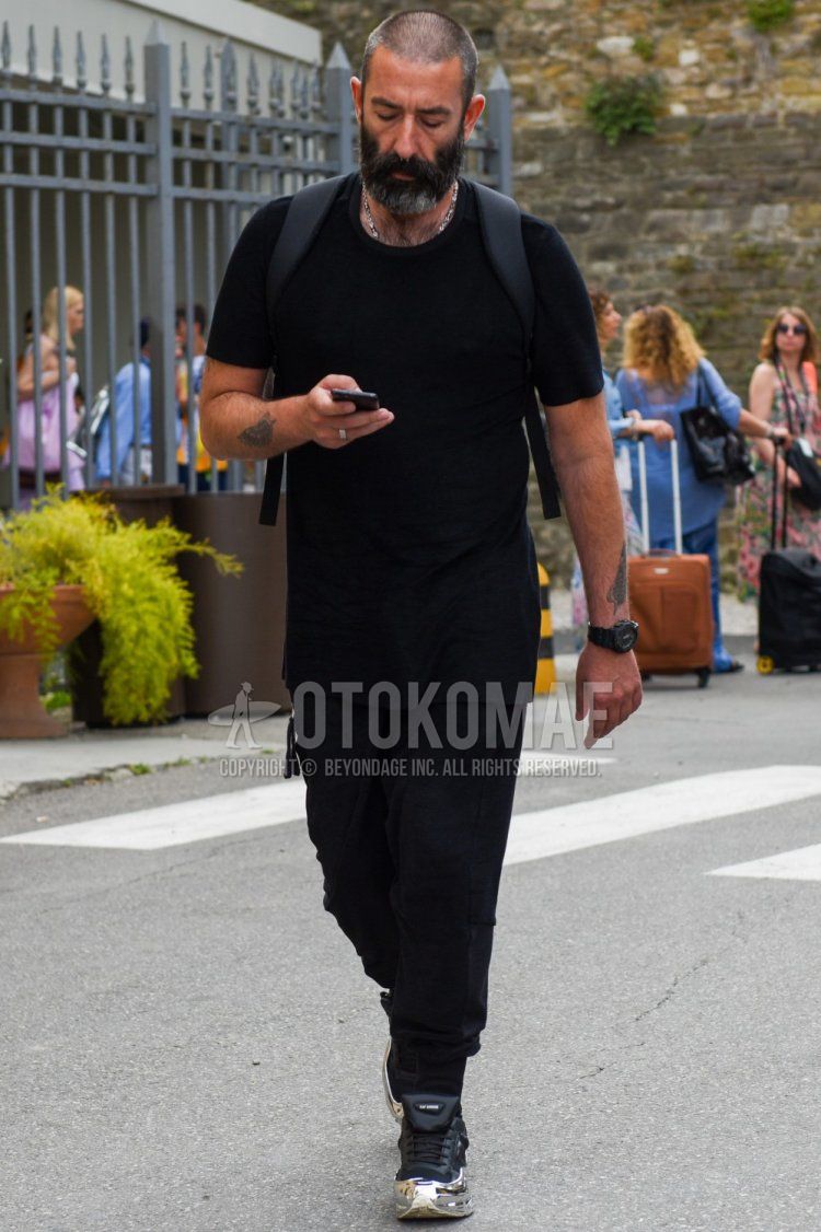 Men's summer coordinate and outfit with plain black t-shirt, plain black jogger pants/ribbed pants, and Raf Simons Adidas Oswego black low-cut sneakers.