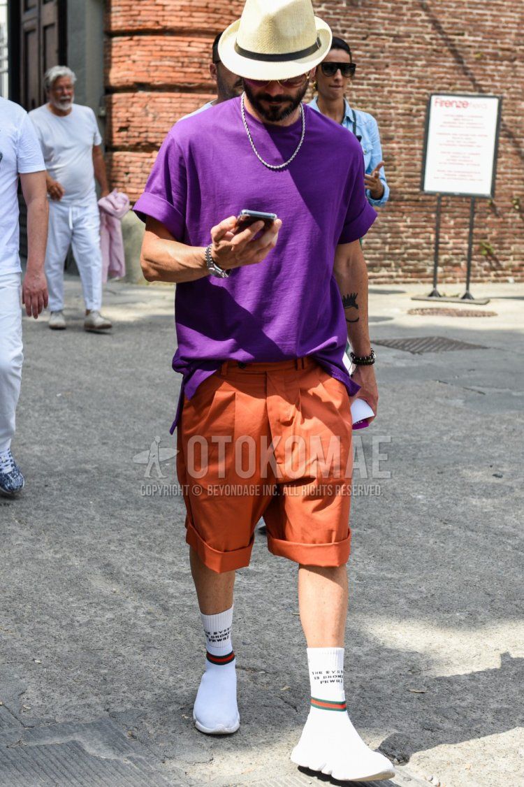 Summer men's coordinate and outfit with solid beige hat, solid purple t-shirt, solid orange beltless pants, solid white socks, and white high-cut sneakers.