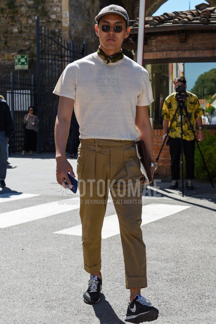 Gray cap baseball cap, solid black/gold sunglasses, brown stole bandana/neckerchief, solid white t-shirt, solid beige beltless pants, Nike Undercover Daybreak black low cut sneakers, solid brown clutch bag/second bag/drawstring bag with a summer men's coordinate and outfit.