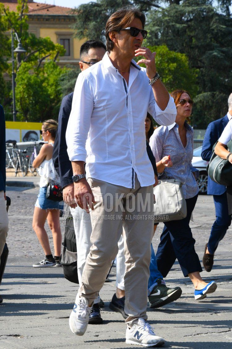 Men's spring/summer coordinate and outfit with plain sunglasses, plain white shirt, plain beige chinos, and New Balance white/gray low-cut sneakers.