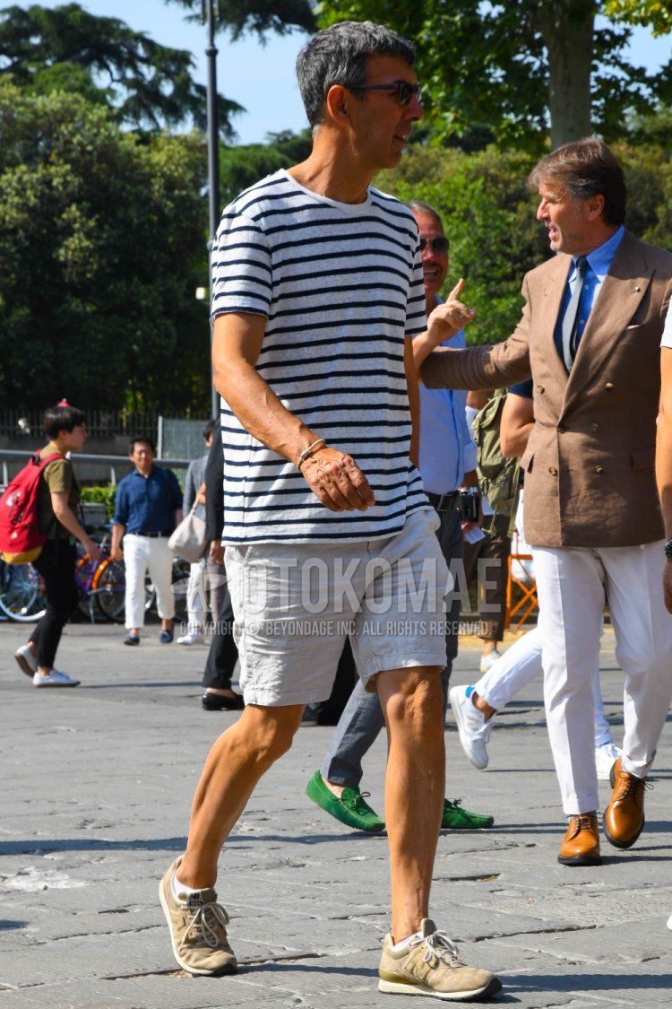 Men's summer coordinate and outfit with plain sunglasses, white/navy striped t-shirt, plain gray/white shorts, and New Balance 996 beige low-cut sneakers.