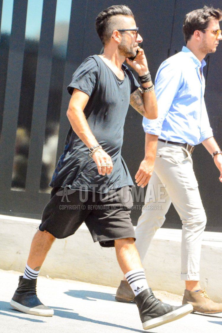 Men's summer coordinate and outfit with plain black T-shirt, plain black shorts, Adidas white big logo socks, and black high-cut sneakers.