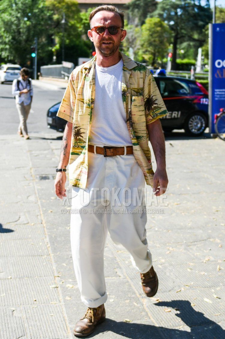 Summer men's coordinate and outfit with brown tortoiseshell sunglasses, short-sleeved beige top/inner shirt, plain white t-shirt, plain beige leather belt, plain white cotton pants, and brown work boots.