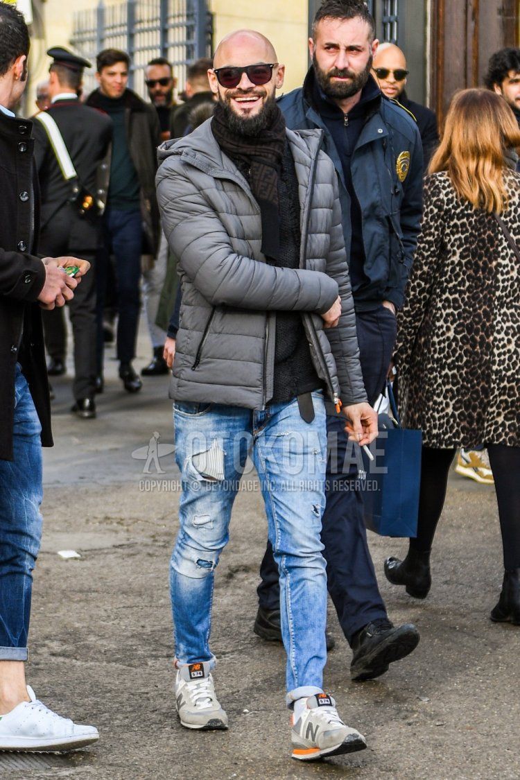 Men's fall/winter coordinate and outfit with plain sunglasses, Fendi black and brown scarf/stall, plain gray down jacket, plain blue damaged jeans, and New Balance 574 gray low-cut sneakers.
