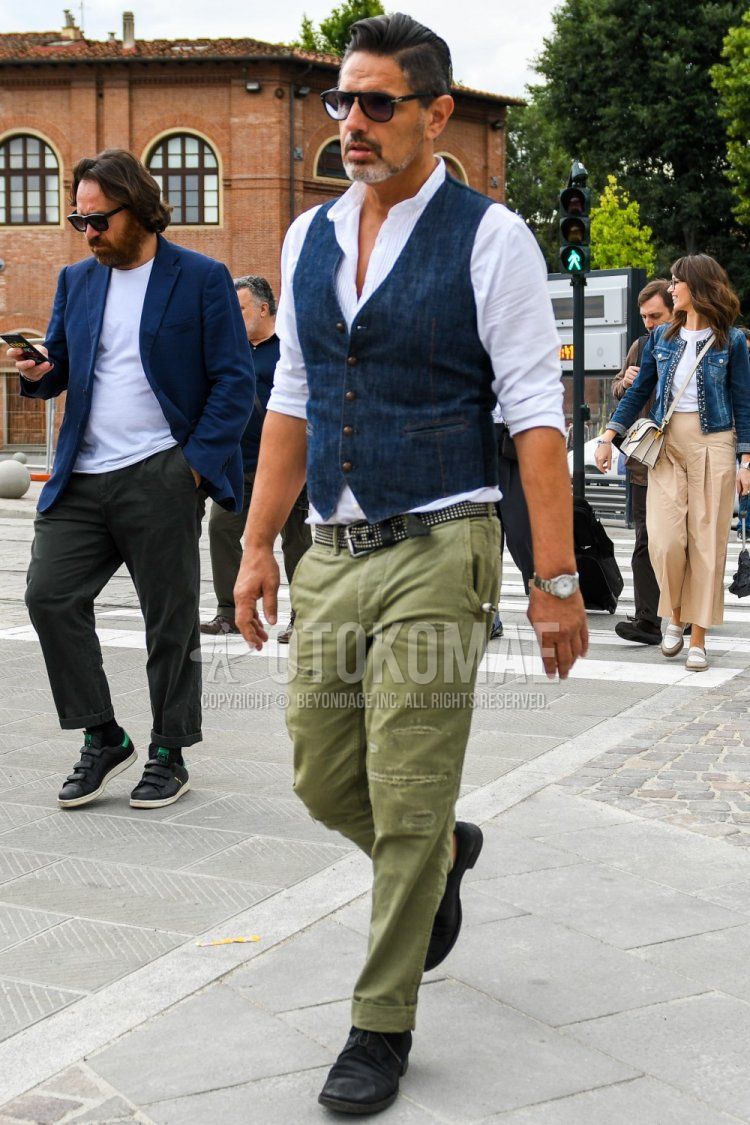 Men's spring/summer coordinate and outfit with plain sunglasses, plain blue gilet, plain white shirt, black leather belt, plain olive green chinos, and black boots.