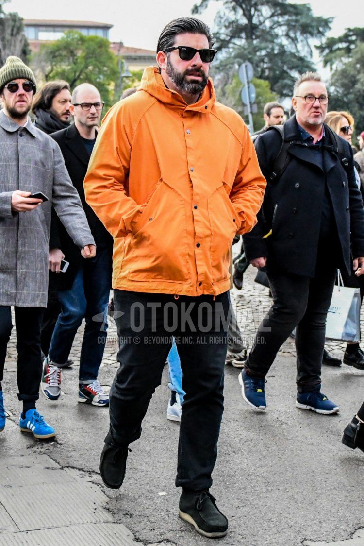 Men's spring and fall coordinate and outfit with plain sunglasses, plain orange mountain parka, plain black cotton pants, and black wallaby boots.