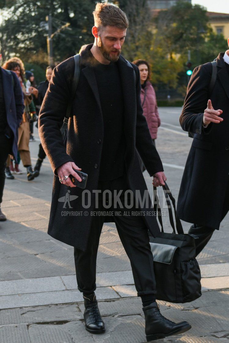 Men's fall/winter outfit with plain black chester coat, plain black sweater, plain black slacks, plain black socks, black boots, and plain black tote bag.