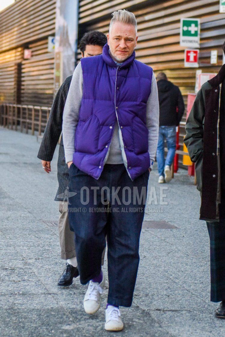 Men's fall/winter coordinate and outfit with a solid purple down jacket, solid gray sweatshirt, solid navy denim/jeans, solid wide-leg pants, solid purple socks, and white low-cut sneakers.