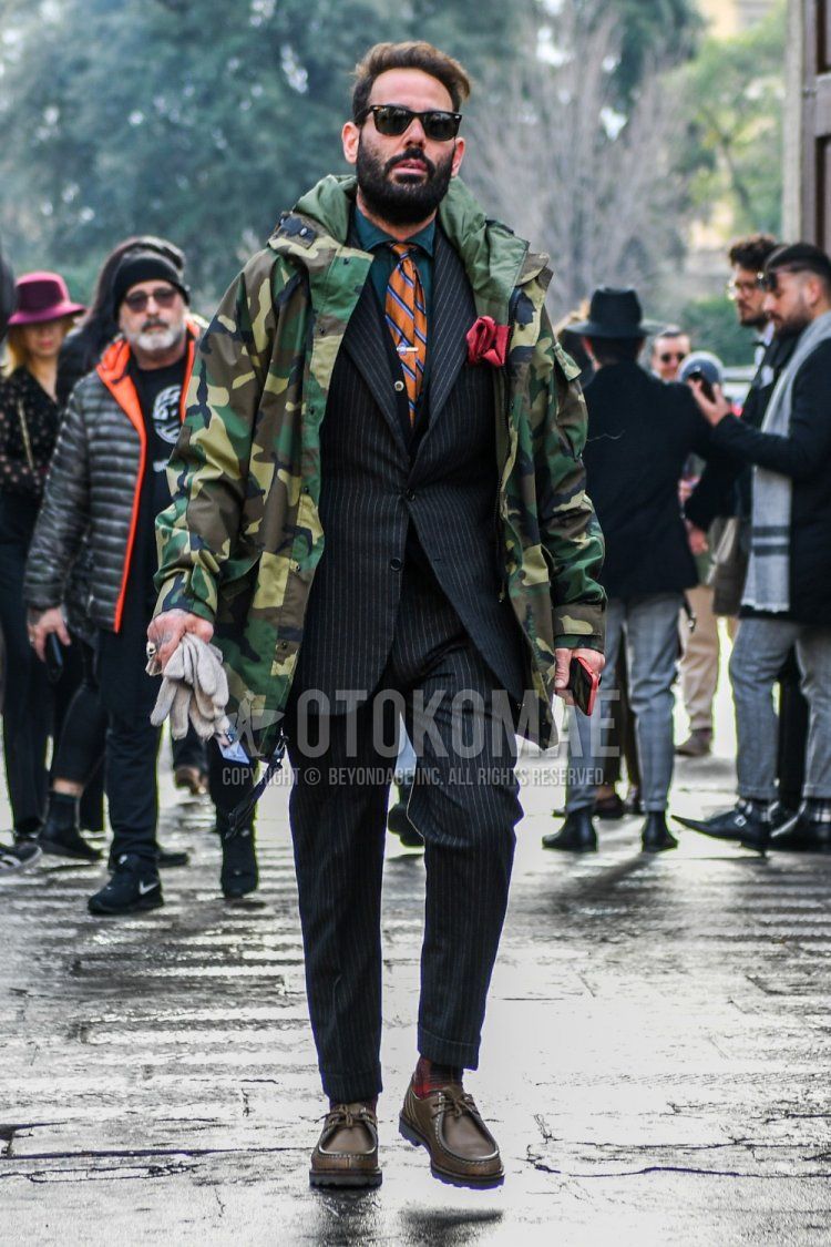 Winter men's coordinate and outfit with solid color sunglasses, multi-color camouflage mountain parka, multi-color camouflage hooded coat, solid color green shirt, solid color red socks, brown leather shoes, black striped suit, orange leopard tie.