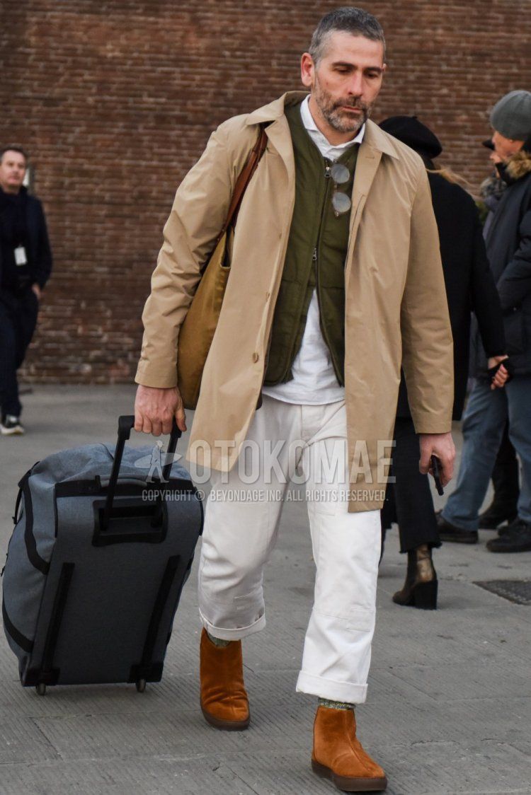 Men's fall/winter outfit with solid beige stainless steel collar coat, solid olive green inner down, pullover solid white shirt, solid white cotton pants, multi-colored socks socks, suede brown boots, and solid gray suitcase.