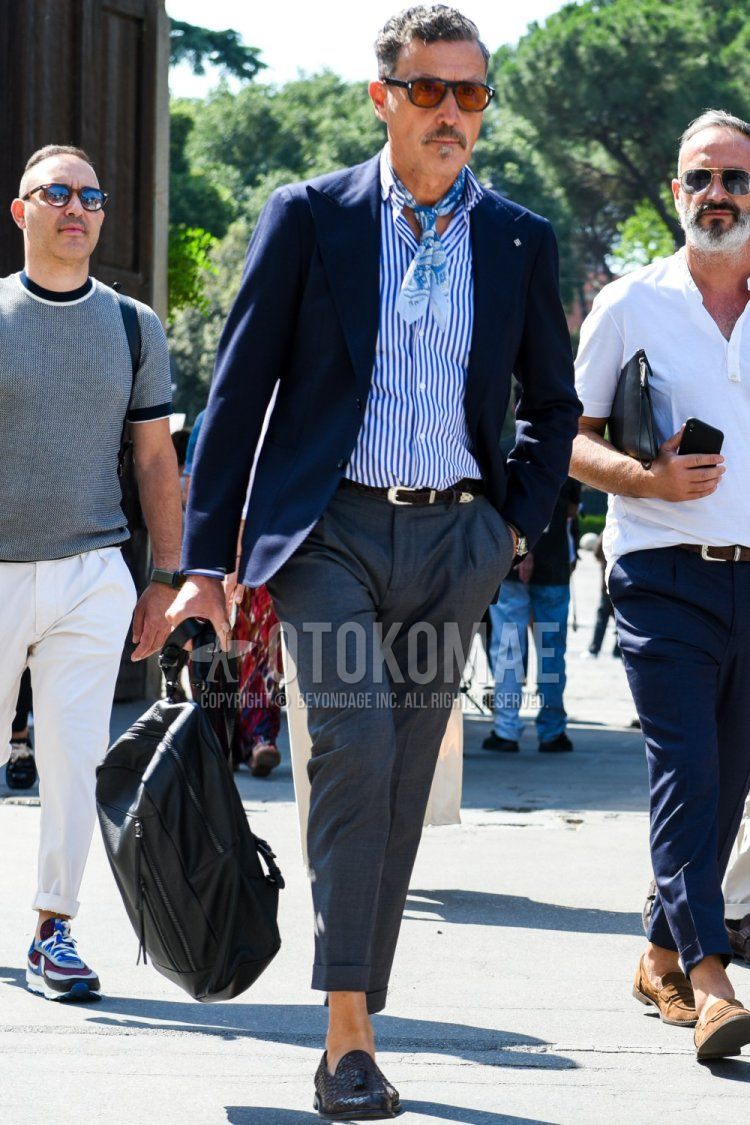 Solid black sunglasses, light blue stole bandana/neckerchief, solid navy tailored jacket, blue and white striped shirt, solid brown leather belt, solid gray slacks, solid gray cropped pants, brown tassel loafer leather shoes, solid black backpack The following is a spring/summer men's coordinate/outfit with the following items.