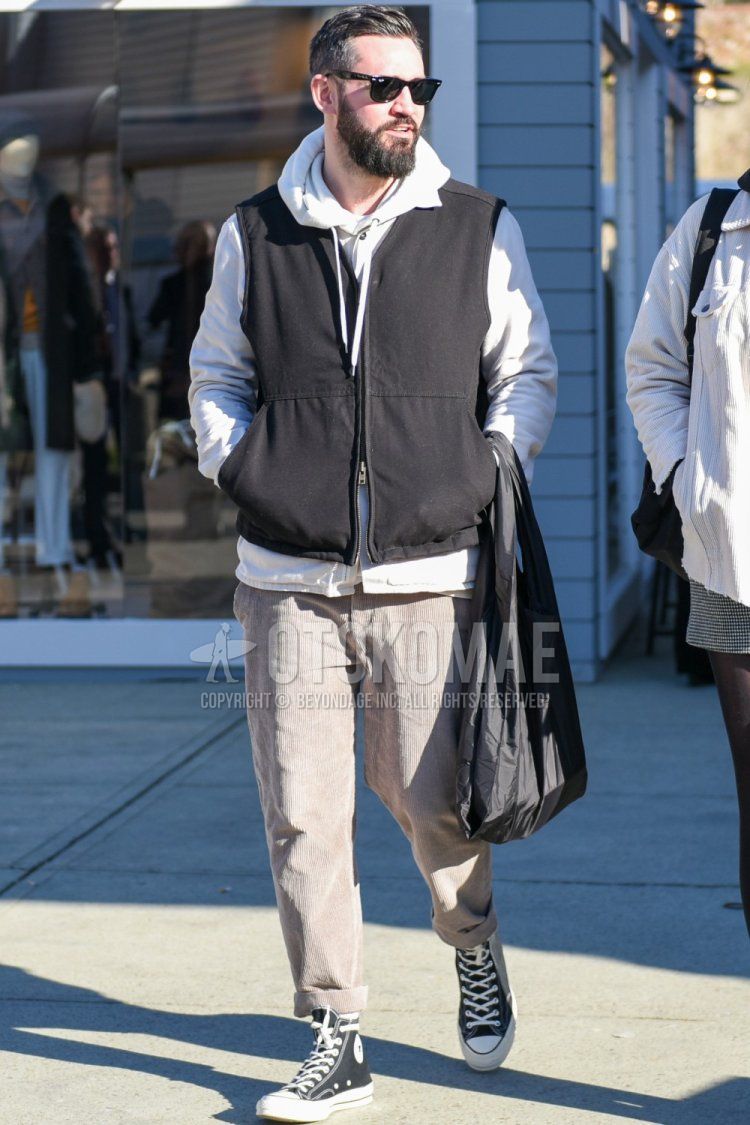 Men's fall/winter coordinate and outfit with Ray-Ban Wayfarer Wellington solid black sunglasses, solid black casual vest, solid gray hoodie, solid beige winter pants (corduroy, velour), solid white socks, and Converse All Star black high-cut sneakers.
