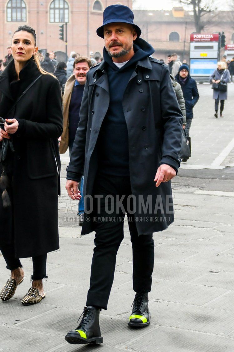 Winter men's coordinate and outfit with plain navy hat, plain black trench coat, plain navy hoodie, plain black ankle pants, and black boots.