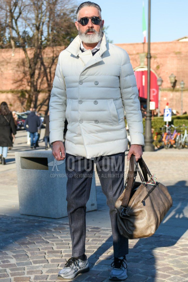 Teardrop solid black sunglasses, solid white down jacket, solid black sweater, solid white shirt, solid gray slacks, solid gray ankle pants, solid black socks, solid gray low-cut sneakers, and solid beige Boston bag for men in fall and winter Outfit.