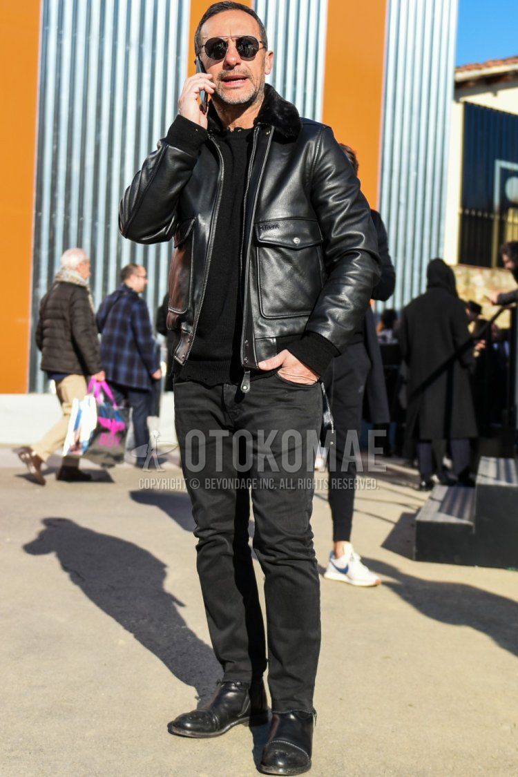 Men's fall/winter coordinate/outfit with plain silver sunglasses, plain black leather jacket (other than rider's), plain black sweater, plain dark gray denim/jeans, and black boots.