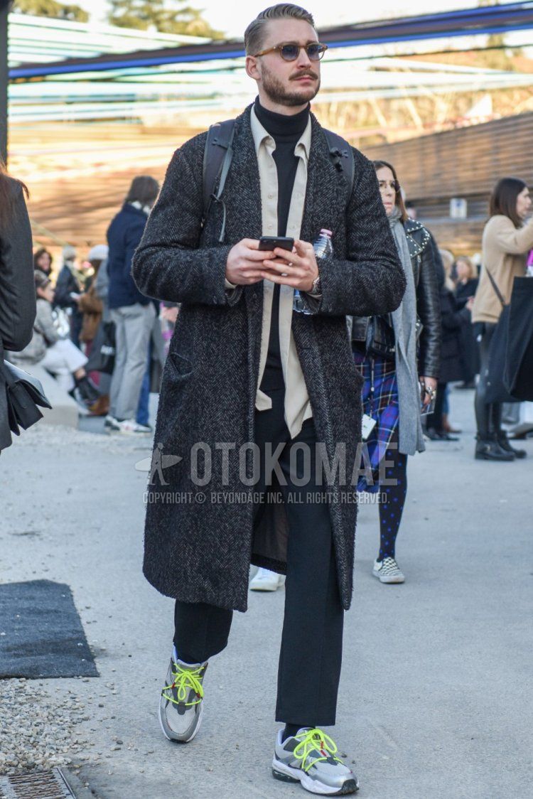 Men's fall/winter outfit with plain brown sunglasses, gray herringbone chester coat, solid beige shirt, solid gray turtleneck knit, solid gray slacks, solid gray ankle pants, solid gray socks, and gray low-cut sneakers .
