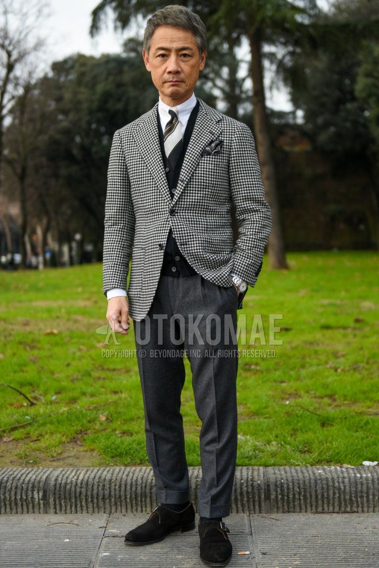 Men's fall/winter coordinate and outfit with gray checked tailored jacket, solid black cardigan, solid white shirt, solid gray slacks, solid navy socks, suede brown monk shoe leather shoes, and multi-colored regimental tie.