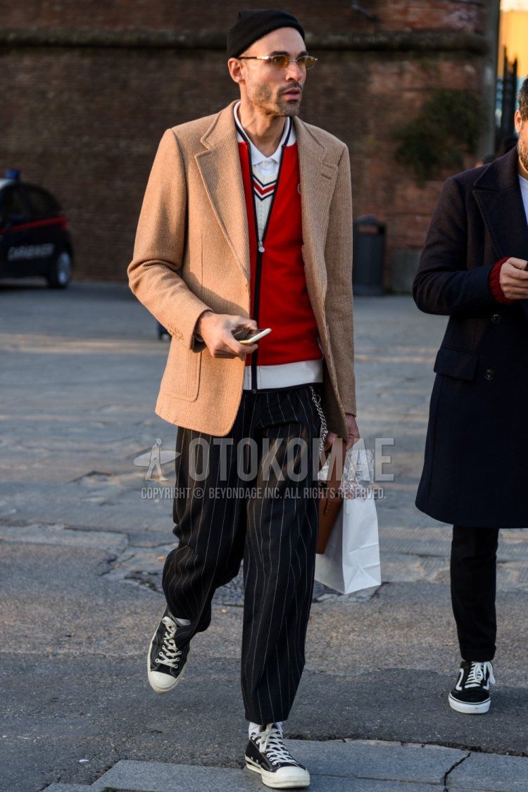Solid black knit cap, solid gold glasses, solid beige tailored jacket, solid red cardigan, solid white Tilden sweater, solid white shirt, dark gray striped slacks, dark gray striped ankle pants, solid white socks, converse Chuck Taylor black low-cut sneakers for men's fall and winter outfits.