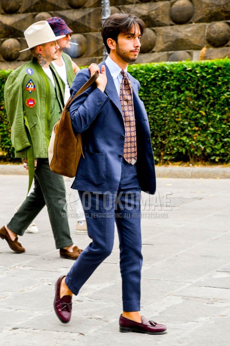 Men's spring and autumn coordination and outfit with plain white shirt, brown tassel loafer leather shoes, plain brown tote bag, plain gray suit and brown necktie.