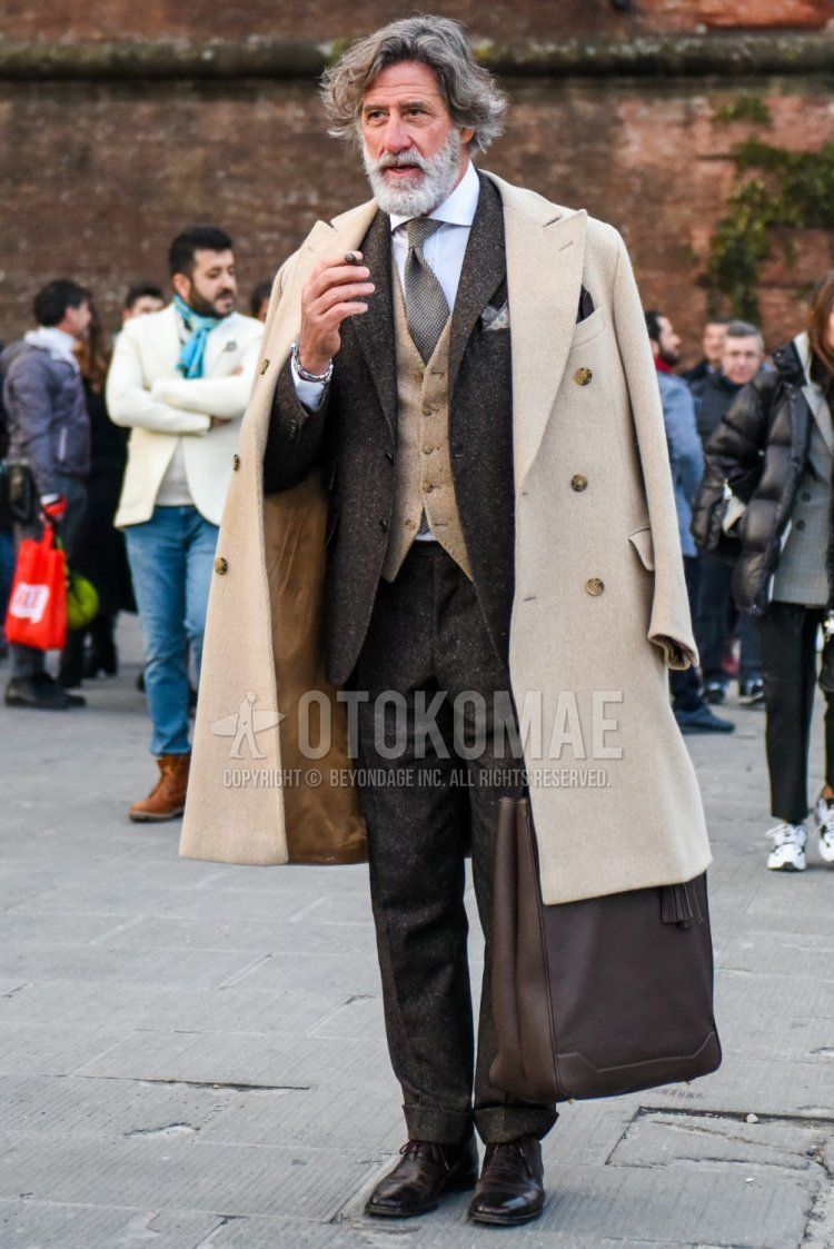 Winter men's coordinate and outfit with plain beige chester coat, plain beige gilet, plain white shirt, brown straight tip leather shoes, plain brown tote bag, plain brown suit and brown necktie.