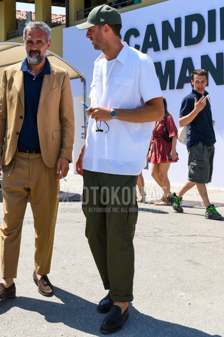 Summer/spring men's coordinate and outfit with New Era green one-pointed baseball cap, plain white t-shirt, short-sleeved plain white shirt, olive green plain cargo pants, and black coin loafer leather shoes.