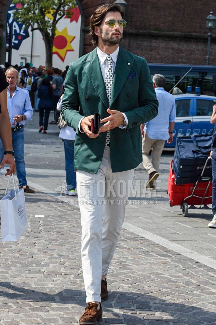 Men's spring and autumn coordinate and outfit with plain silver sunglasses, plain green tailored jacket, plain white shirt, plain beige chinos, suede brown tassel loafer leather shoes, and white small print tie.