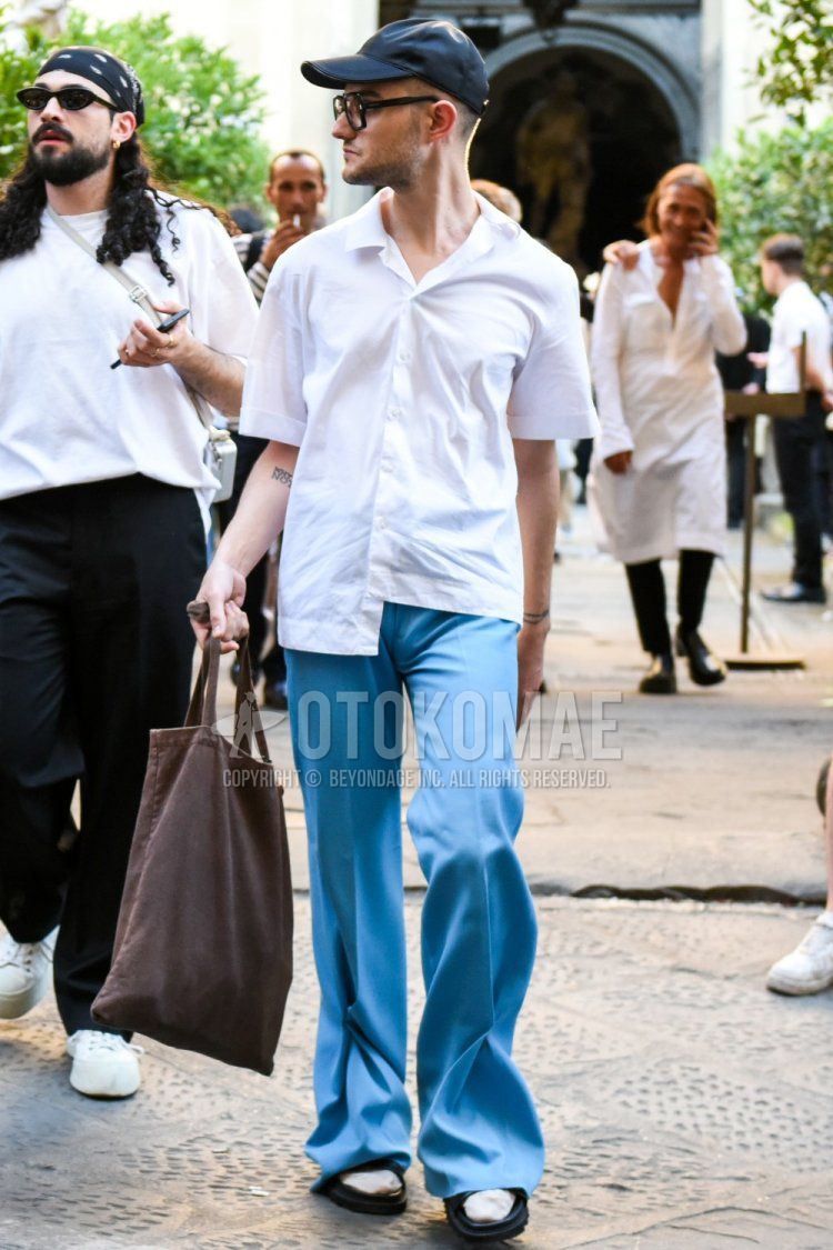 Men's spring/summer coordinate and outfit with solid black baseball cap, solid black sunglasses, solid white shirt, solid blue slacks, solid white socks, solid black sports sandals, and solid brown tote bag.
