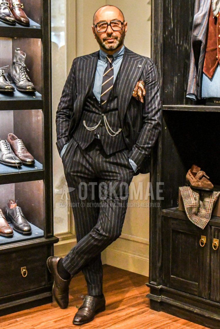 Men's spring and fall coordinate and outfit with plain glasses, plain light blue shirt, plain black socks, brown monk shoes leather shoes, black striped three-piece suit, and black regimental tie.