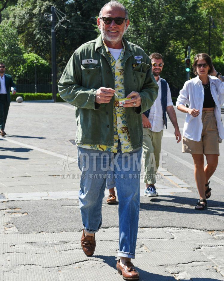 Summer/spring men's coordinate and outfit with plain black sunglasses, plain olive green military jacket (other than MA-1 or M-65), yellow top/inner shirt, plain white t-shirt, plain blue denim/jeans, brown tassel loafer leather shoes.